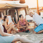 Group of young people chatting and smiling outdoors on a summer camp.